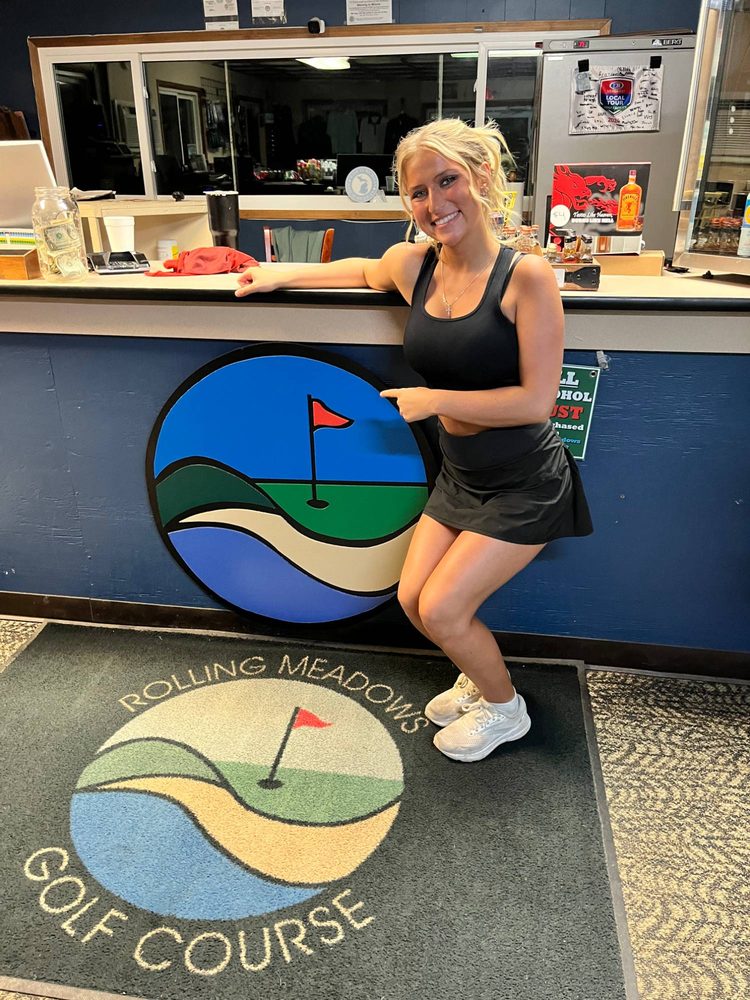 Custom round golf flag logo for Rolling Meadows Golf Course mounted on the pro shop counter, above the matching entrance rug