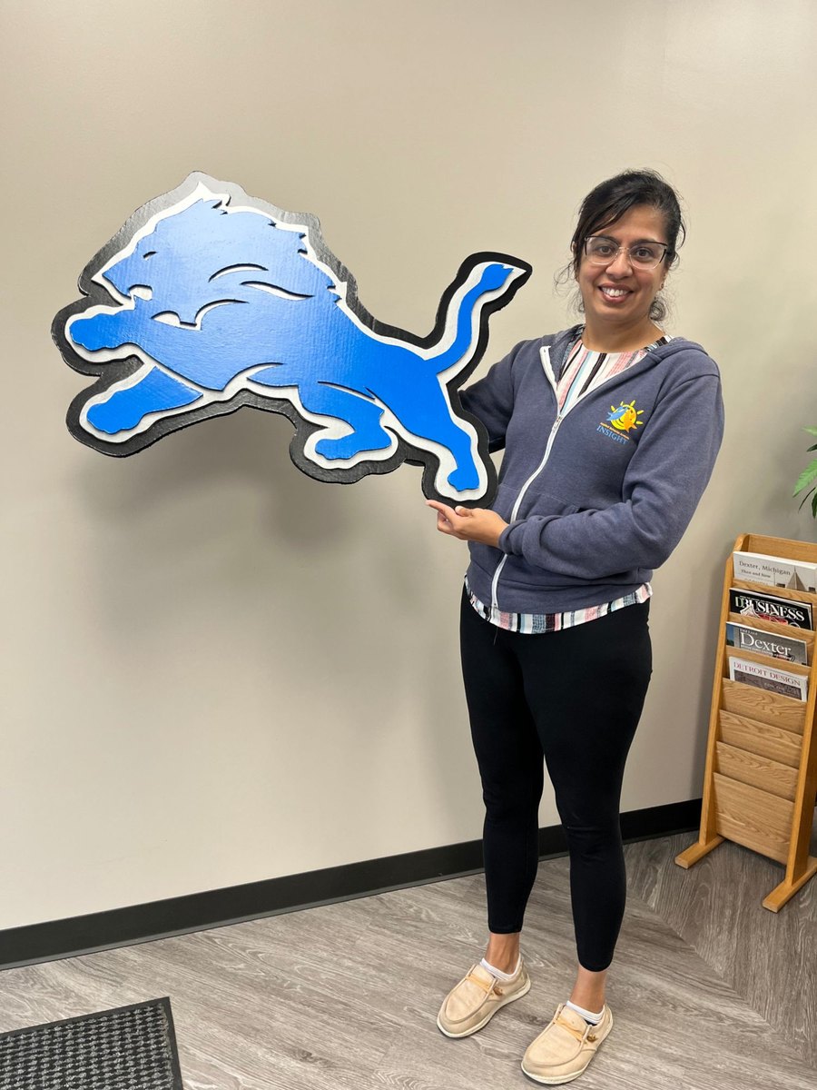 Customer holding a custom Detroit Lions logo cutout in an office