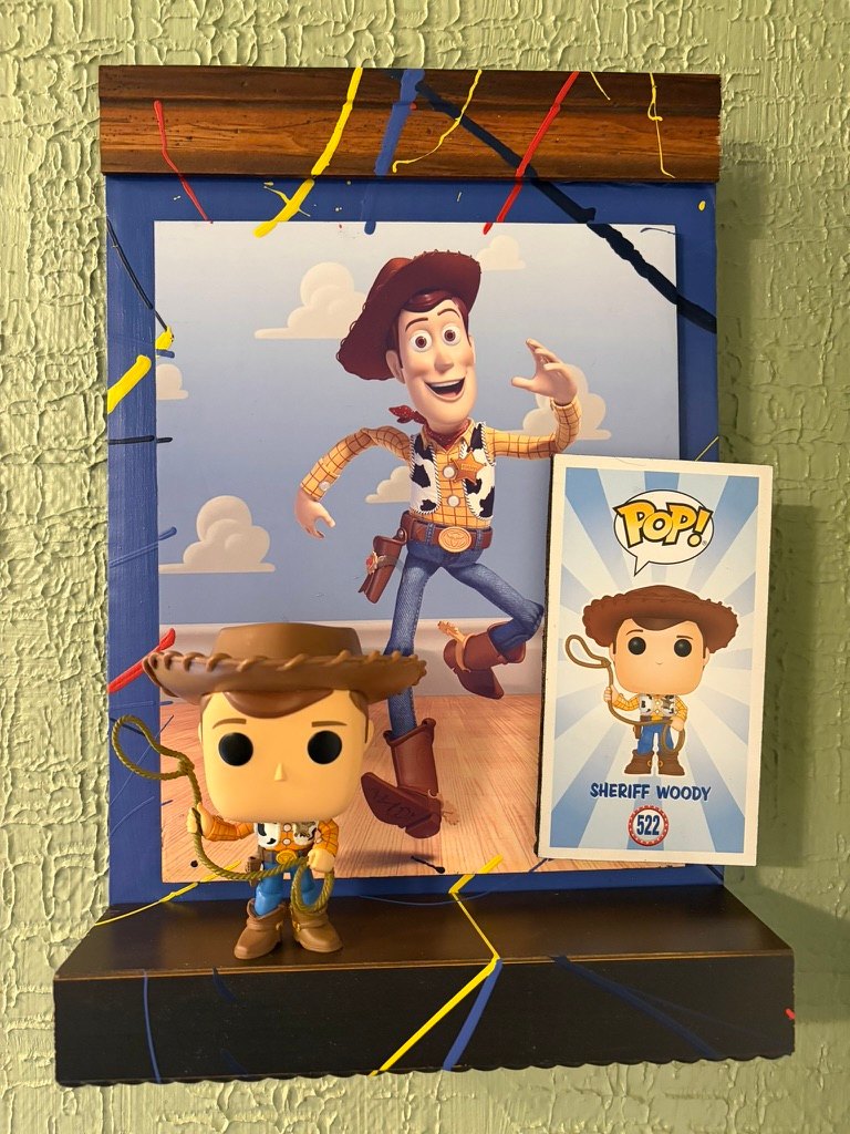 Hand-embellished Toy Story Sheriff Woody poster on a splatter-painted shelf with a Funko Pop Woody and box