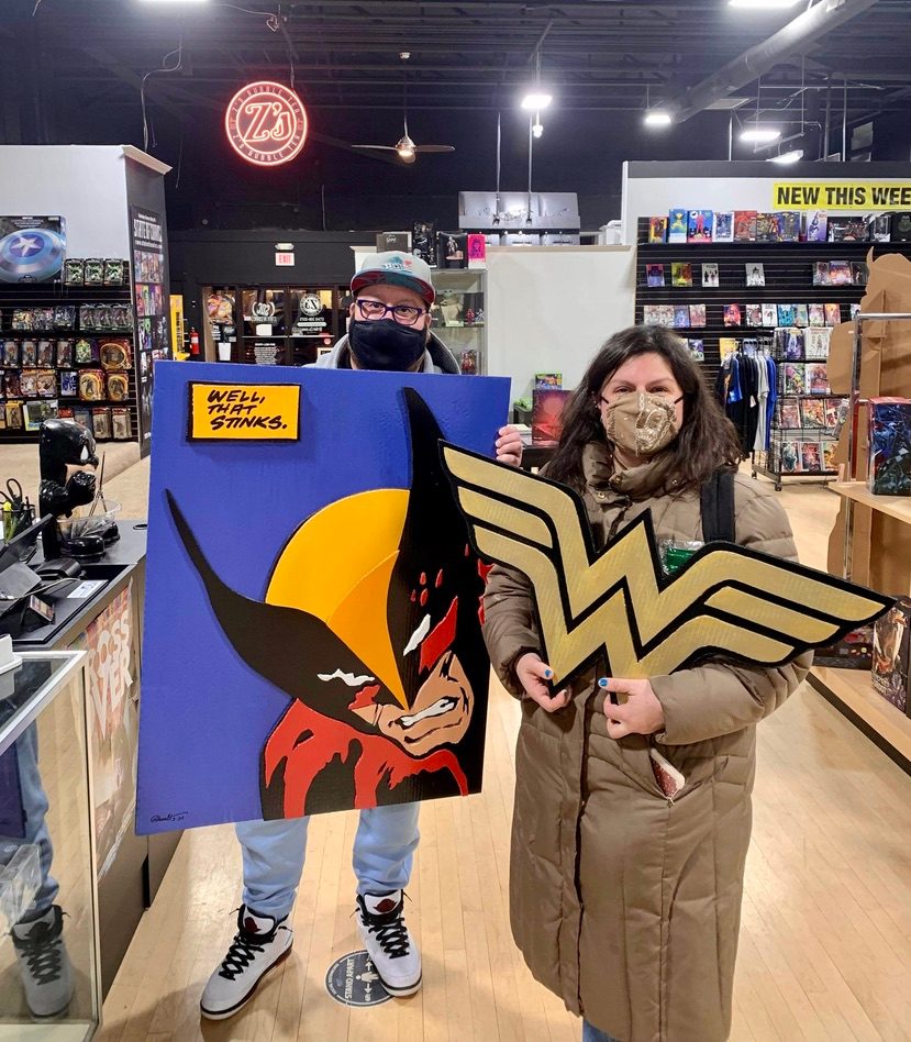 Hand-cut Wolverine Well, that stinks pop-art panel and a gold Wonder Woman logo, held by two customers in a comic shop