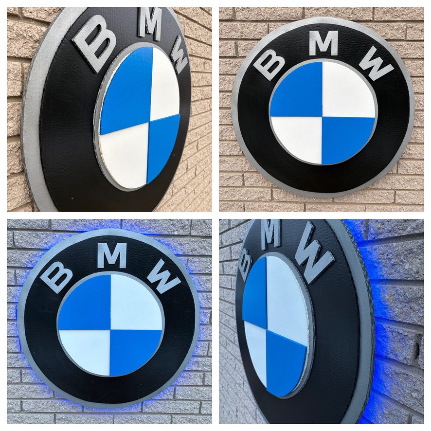 Custom BMW roundel logo cutout in black, silver, blue and white: front and angled views, plus the LED backlit version glowing on a brick wall