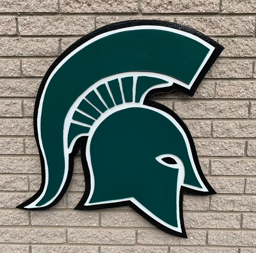 Custom Michigan State Spartan helmet cutout in green, white and black on a brick wall