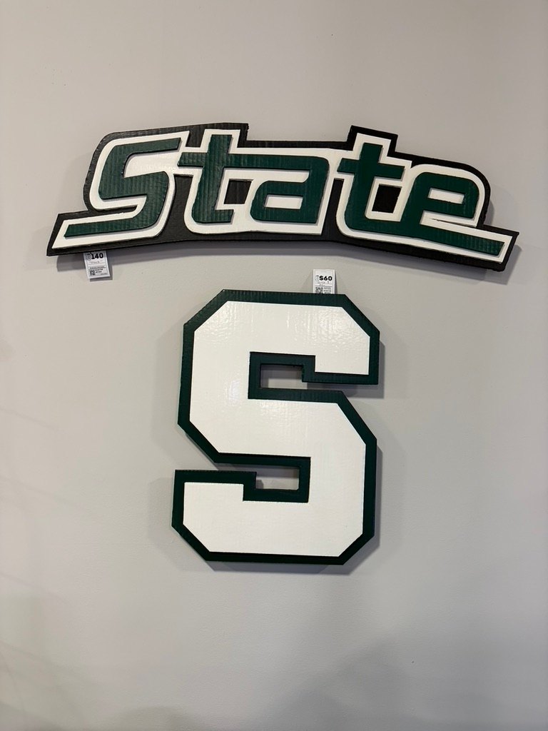 Custom Michigan State State script and white block S cutouts with green trim on a shop wall