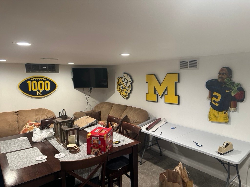 Custom Michigan 1000 football, vintage Wolverine mascot, maize block M and number 2 player portrait cutouts on a basement wall