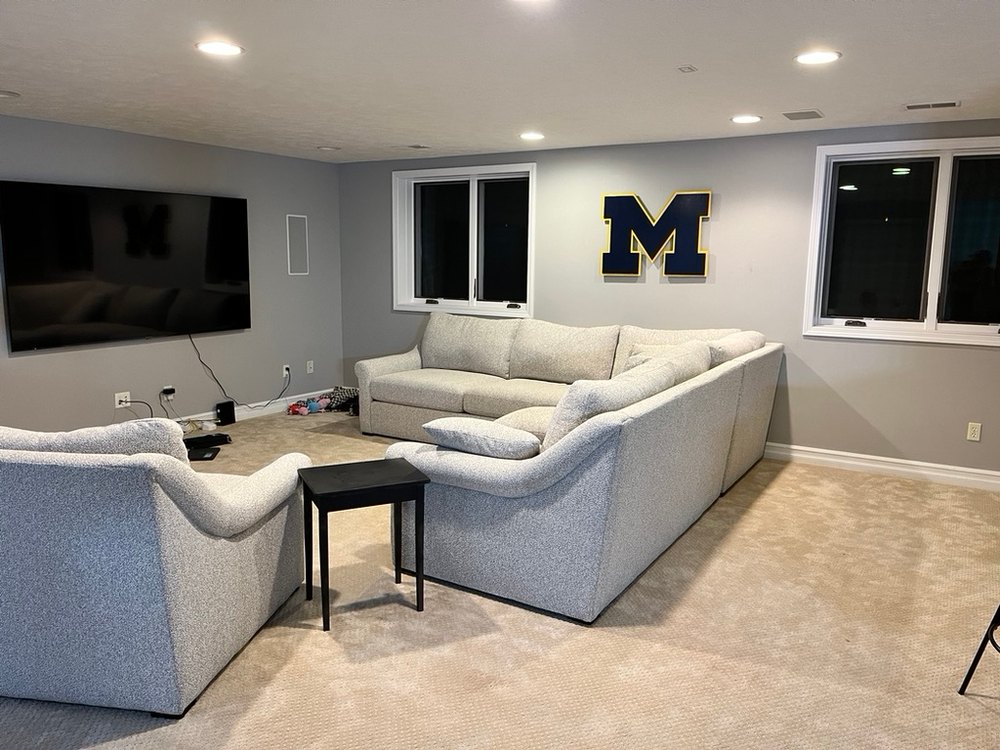 Custom navy Michigan block M cutout with maize trim on the wall of a finished basement living room