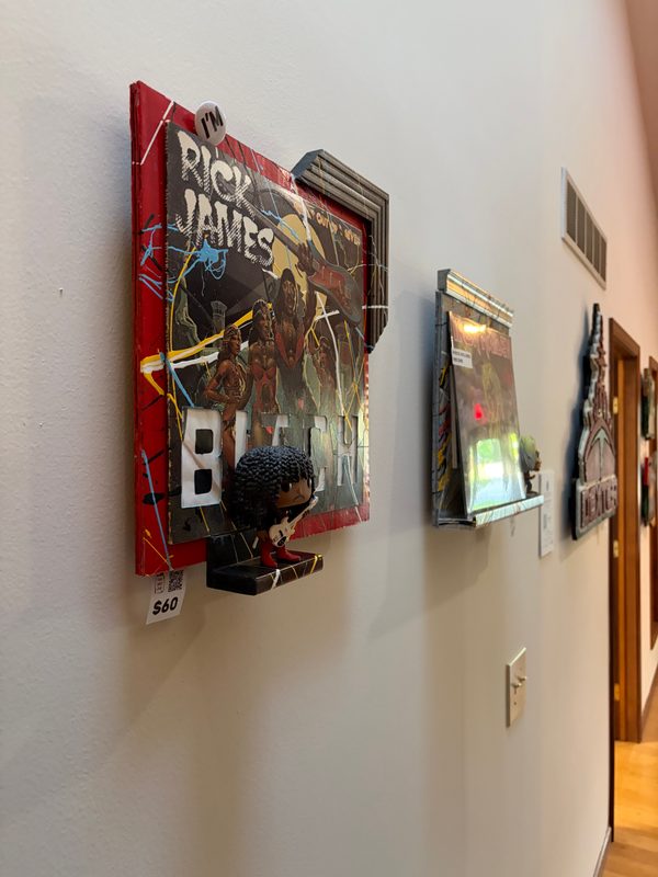 Rick James piece and other record art on the office wall