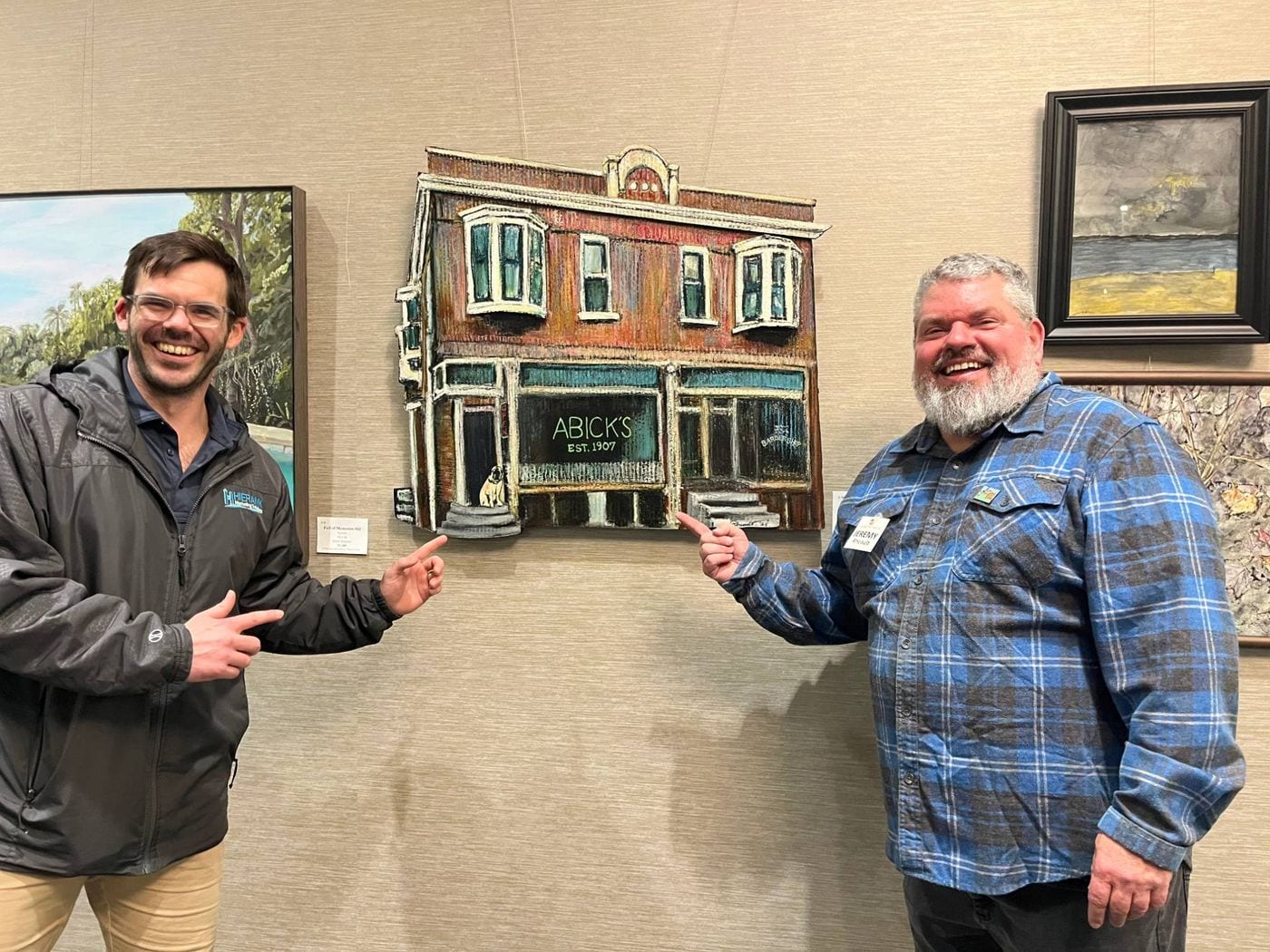 Matt Hall and Jeremy Allen Rheault pointing at Abick’s Shadow on the gallery wall