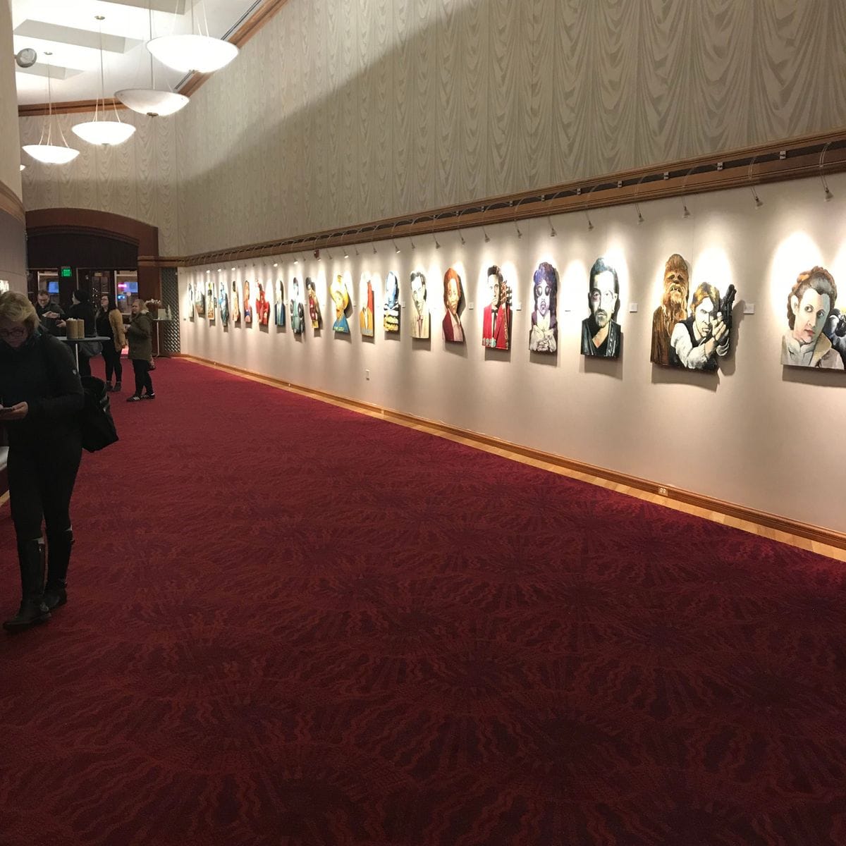 Long carpeted hallway at The Village Theater lined with Jeremy Rheault’s portraits