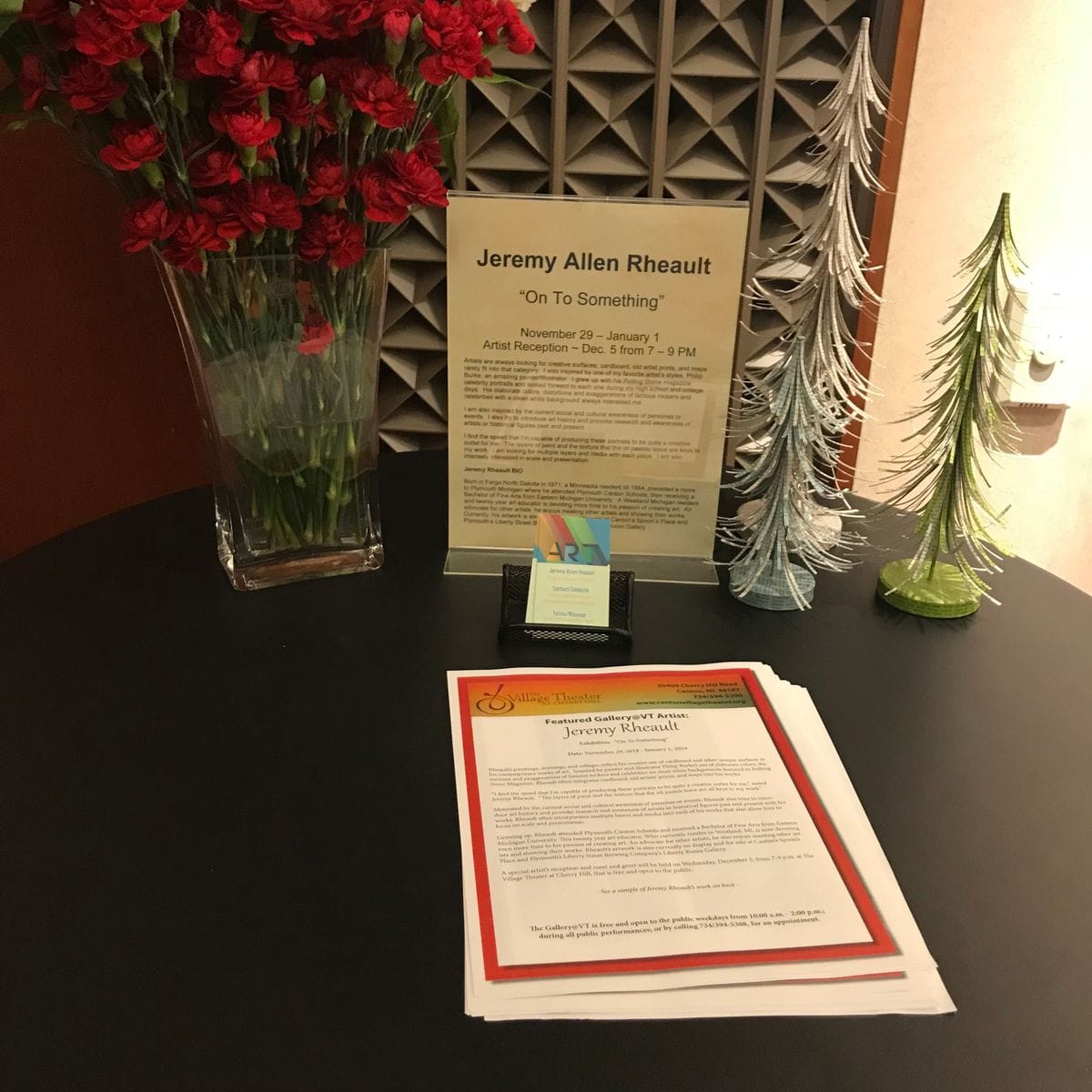Table with an exhibit sign for Jeremy Allen Rheault, On To Something, and stacks of flyers