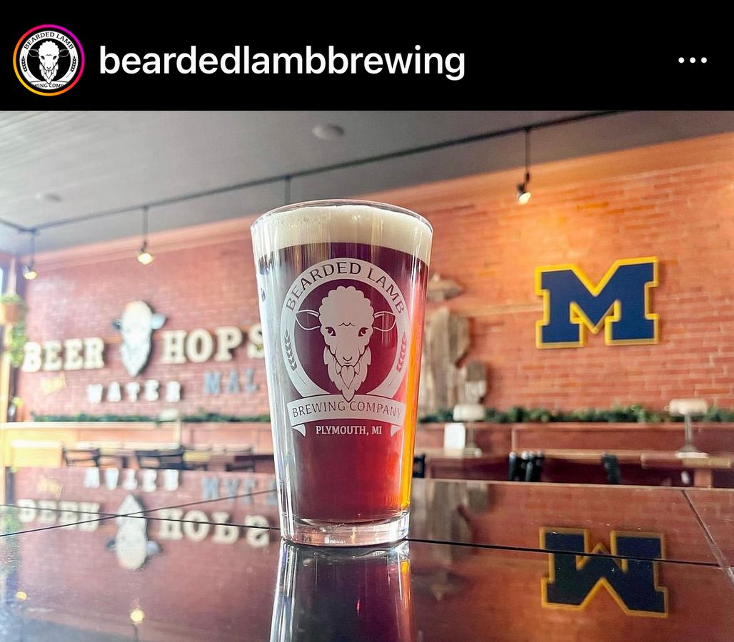 A Bearded Lamb pint glass on the bar with the Michigan M and the Beer Hops wall behind it