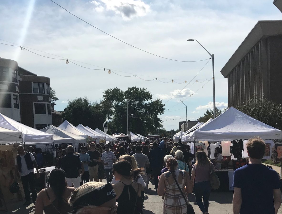 Looking down the Dally in the Alley festival street lined with white tents and a crowd