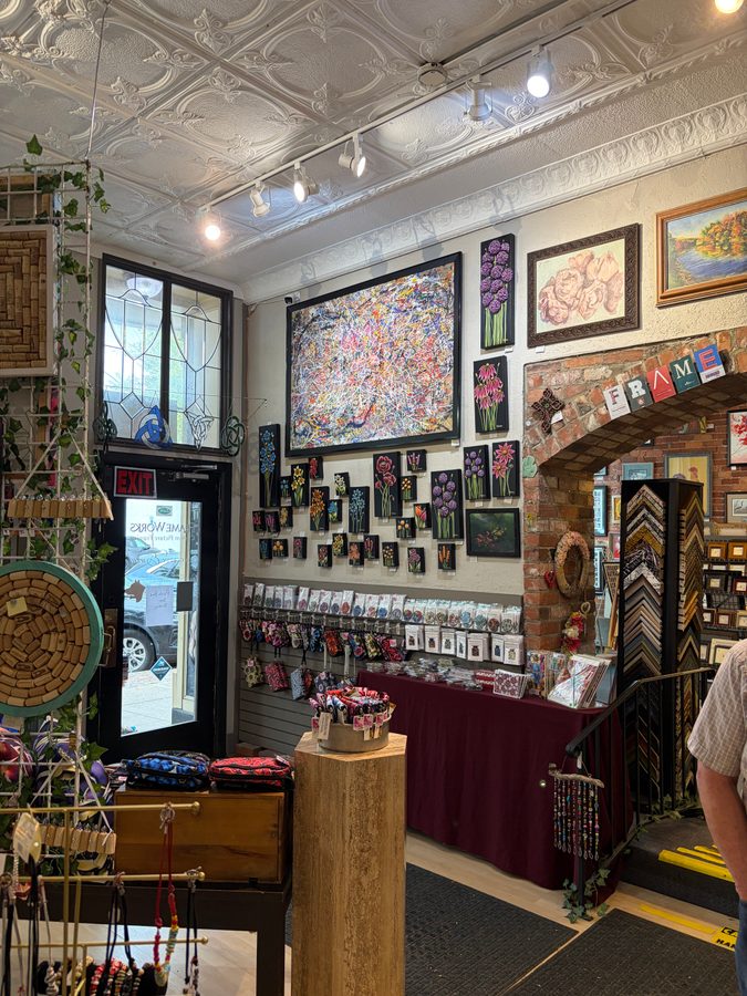 Looking into Frame Works Art Gallery, with Persevere above the door wall, framing samples, cards and gifts under a tin ceiling