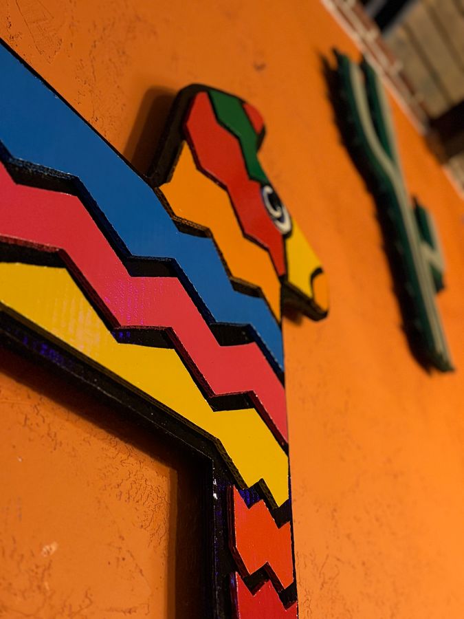 Close-up of the piñata donkey’s zigzag stripes on the orange wall