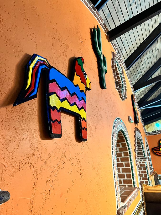 Rainbow piñata donkey on the orange wall at Los Amigos