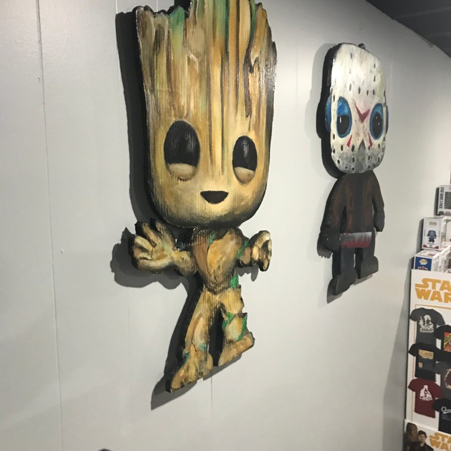Groot and Jason Voorhees cutouts on a white wall beside a shelf of Star Wars Funko Pops
