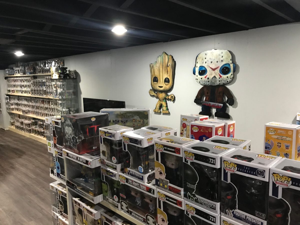 Inside the Popgodz Funko Pop store with shelves of boxed Funko Pops and two hand-cut cutouts, Groot and Jason Voorhees, on the wall