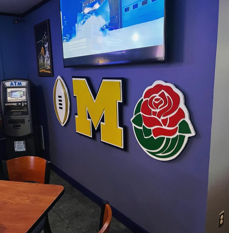 The Michigan M, football and Rose Bowl rose on the blue wall beside the ATM