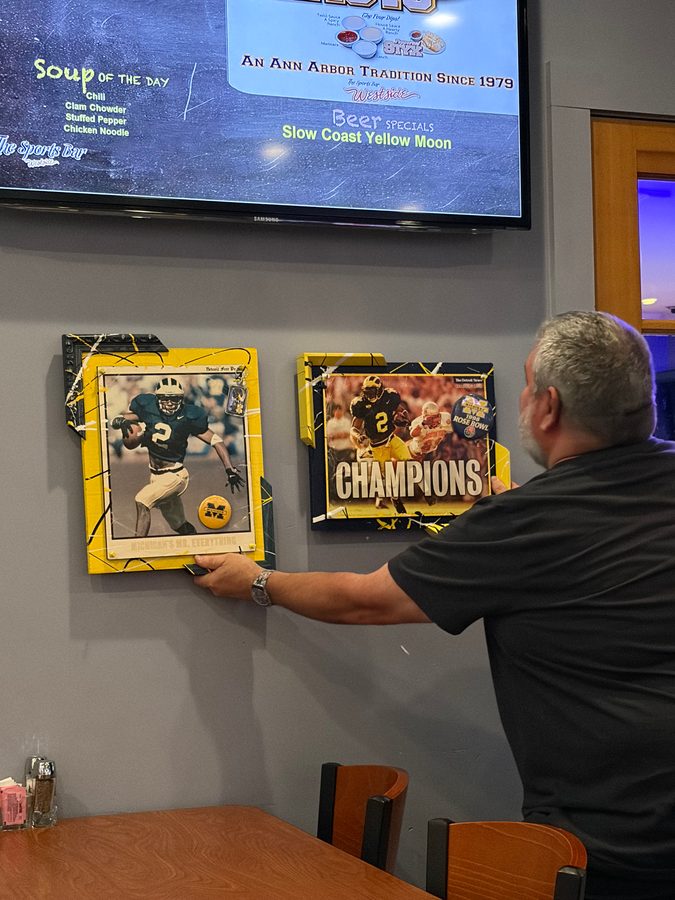 A man hanging the Champions pieces on the wall under a TV