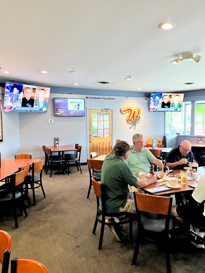 The red and yellow W logo on the wall by the door while diners eat lunch