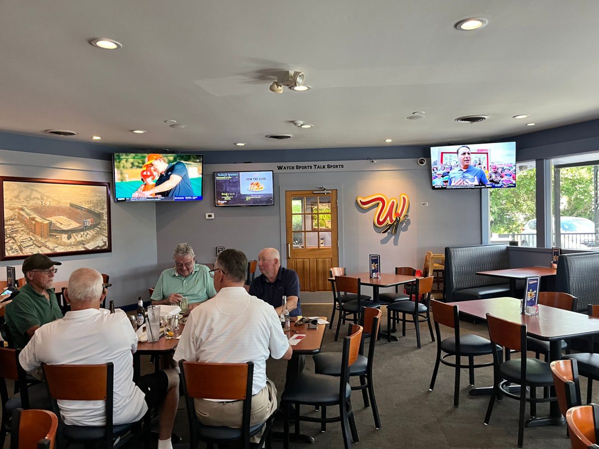 Diners in the dining room with the W logo on the wall beside the wooden door