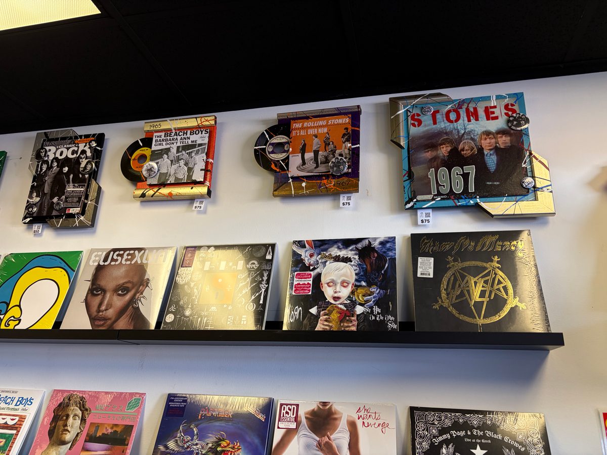 Hand-embellished Rolling Stones piece and other album covers on the wall at Vinyl People Records