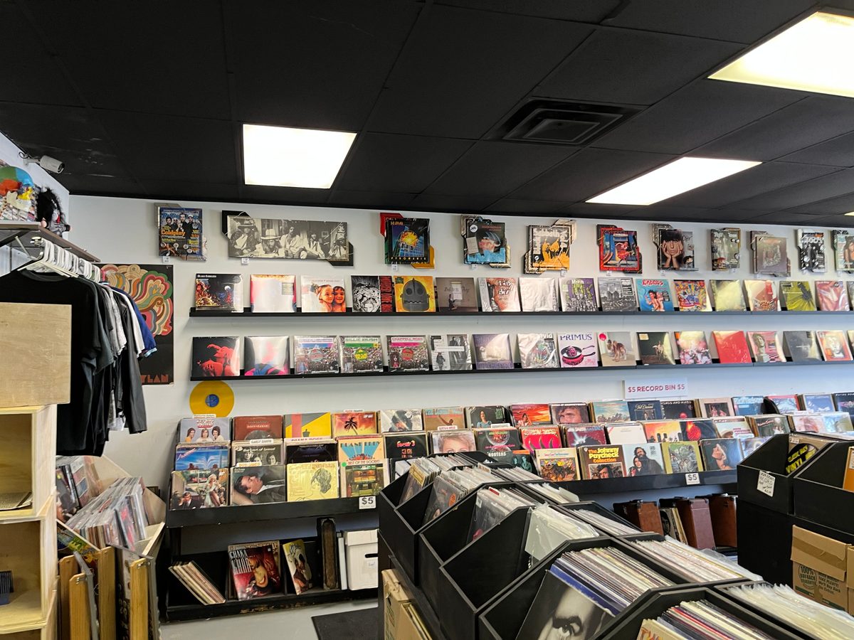 A long wall of vinyl records with hand-embellished album pieces mixed in at Vinyl People Records