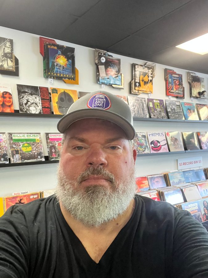 Jeremy Rheault taking a selfie in front of the record wall at Vinyl People Records