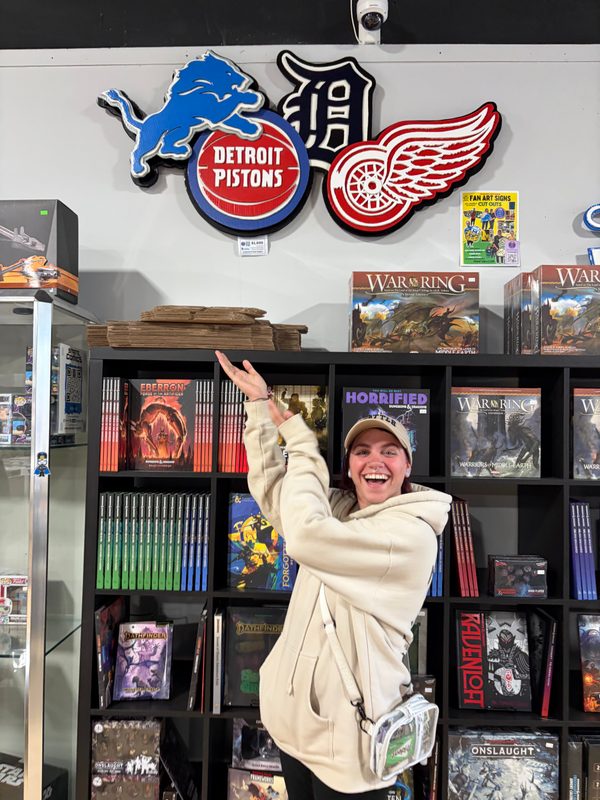 A customer pointing up at the Lions, Tigers, Pistons and Red Wings logo cutouts at State of Comics