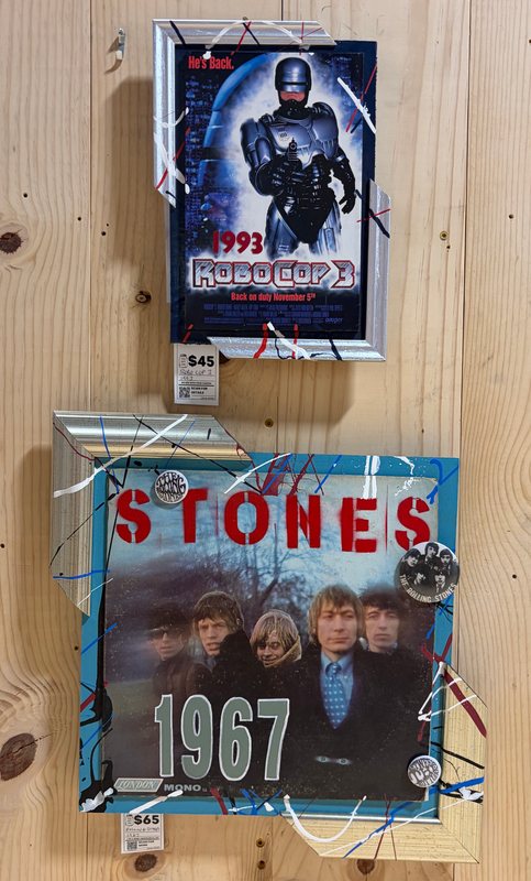 Framed hand-embellished RoboCop 3 poster and Rolling Stones 1967 album art on a pine board